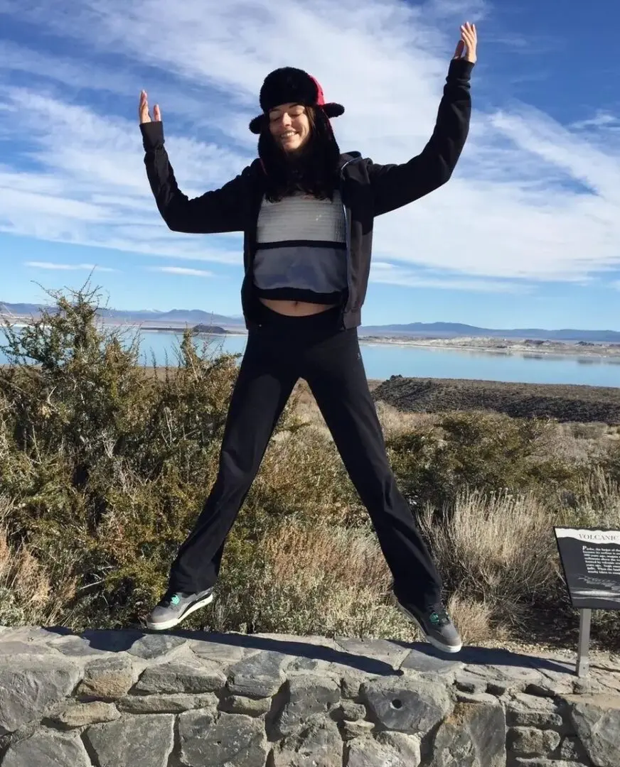 A person jumping in the air on top of a hill.